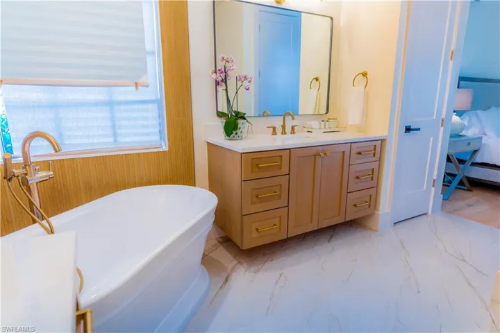 Ensuite bathroom with a freestanding tub, vanity, and light marble finish flooring