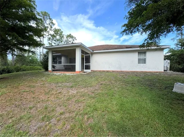 Rear exterior featuring a screened patio with a concrete slab, stucco exterior, and a shingle roof