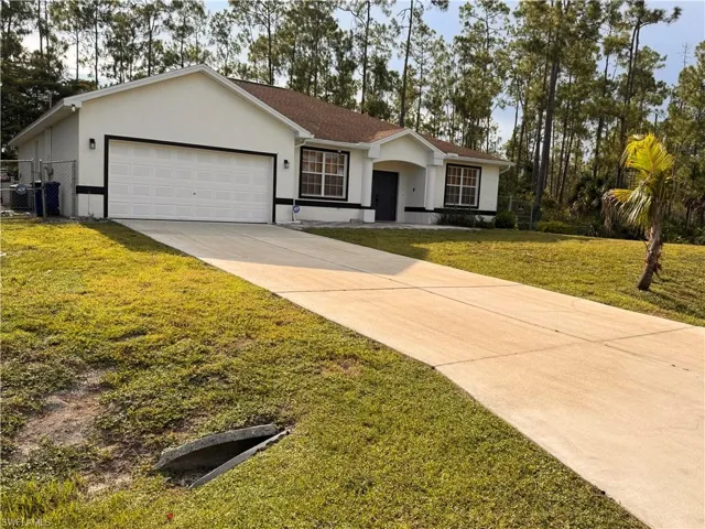 Single-story residence featuring a two-car garage, concrete driveway, and a fenced side yard