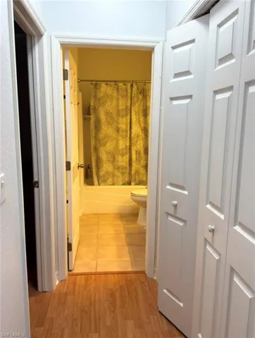 Hardwood-finish flooring extending into the hallway, white paneled doors, and a tiled bathroom floor
