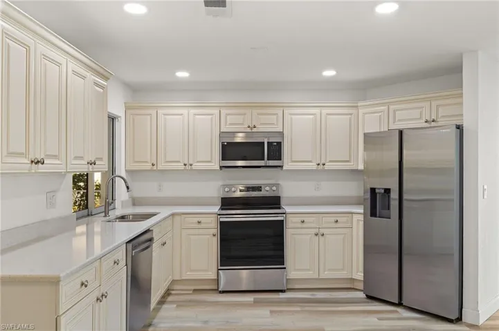 Kitchen with cream cabinets, stainless steel appliances, light hardwood / wood-style flooring, and sink
