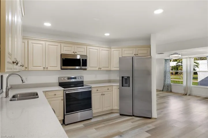 Kitchen featuring cream cabinets, light wood-type flooring, stainless steel appliances, and sink