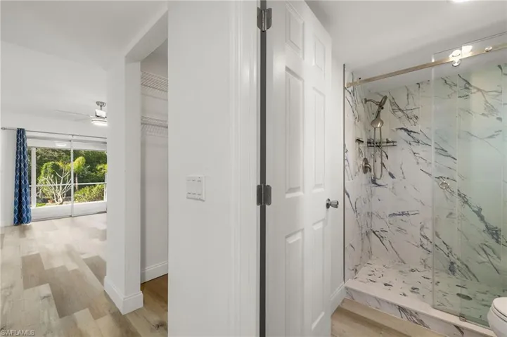 Primary Bathroom with ceiling fan, an enclosed shower, and wood-type flooring