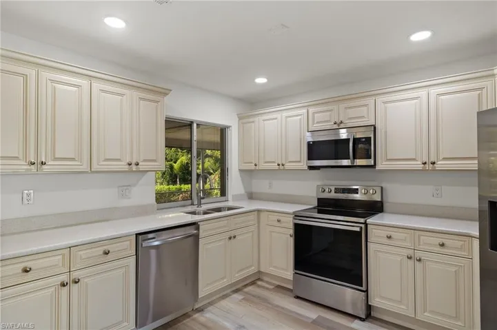 Kitchen with cream cabinets, sink, stainless steel appliances, and light hardwood / wood-style floors
