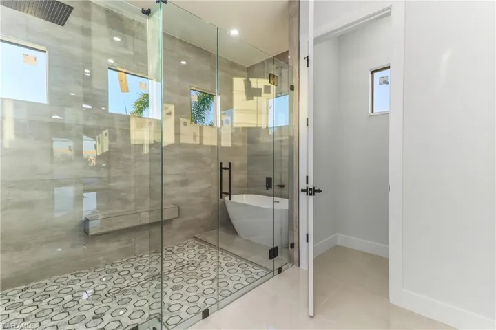 Full bathroom with a shower stall, a freestanding bath, and light tile patterned floors