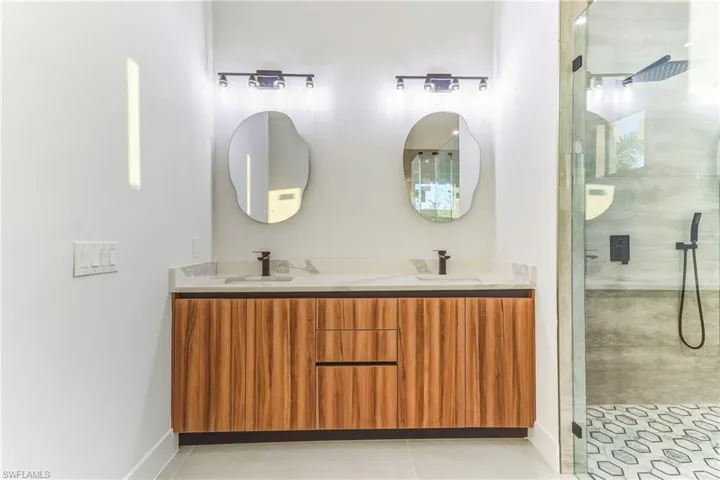 Bathroom featuring a stall shower, double vanity, and light tile patterned flooring