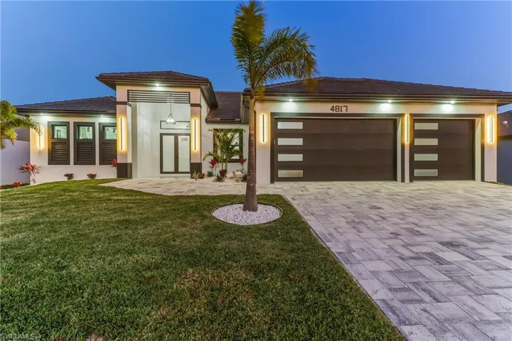 featuring a yard, paver driveway,d 3 car garage