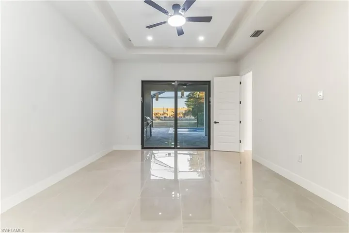 Primary bedroom featuring a ceiling fan, a tray ceiling, light tile patterned flooring, and recessed lighting