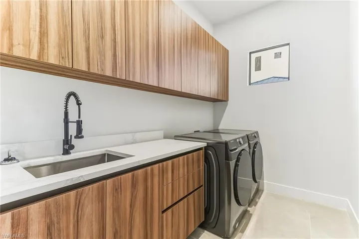 Laundry area with cabinet space, light tile patterned floors, and washing machine and clothes dryer