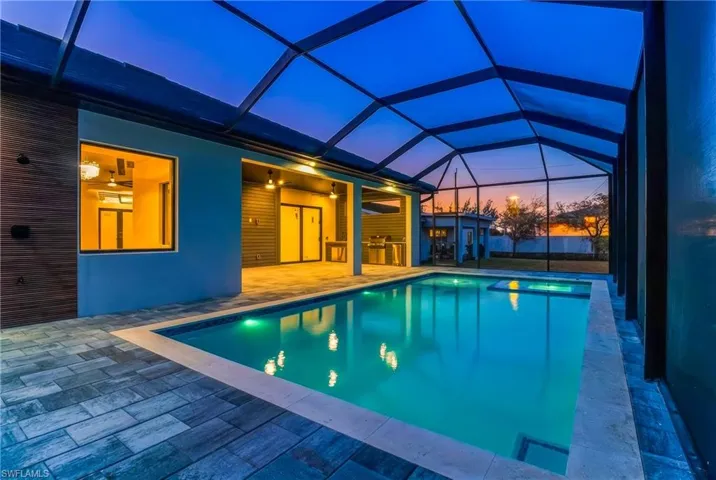 Pool at dusk with an outdoor pool, a patio area, screened enclosure pool cage