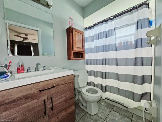Bathroom with toilet, tile patterned flooring, vanity, and curtained shower