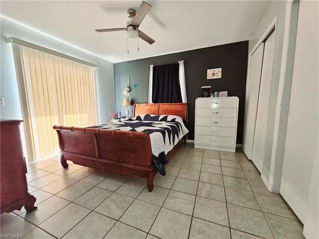Tiled bedroom featuring a ceiling fan and a closet