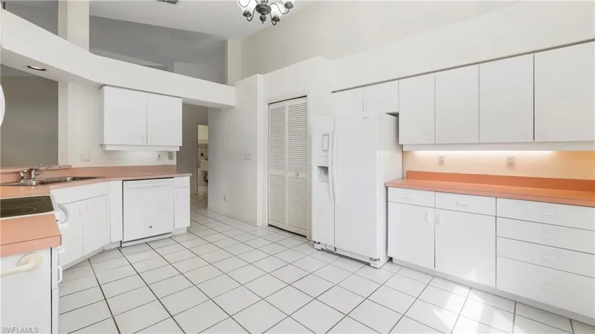 Kitchen with white appliances, light countertops, white cabinetry, a high ceiling, and light tile patterned flooring