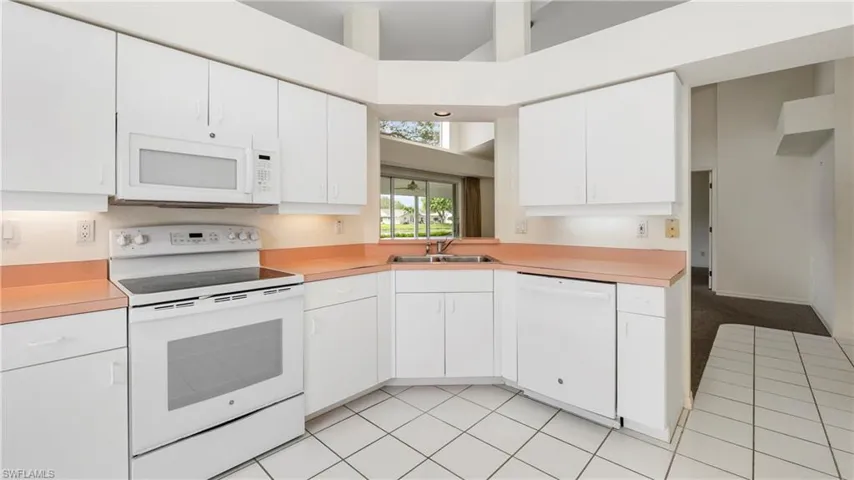 Kitchen featuring white appliances, light countertops, and white cabinets
