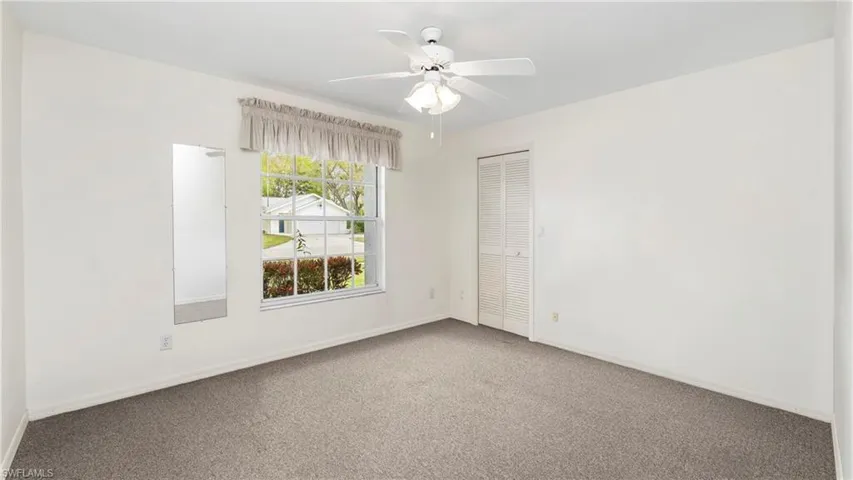 Carpeted spare room featuring ceiling fan and baseboards
