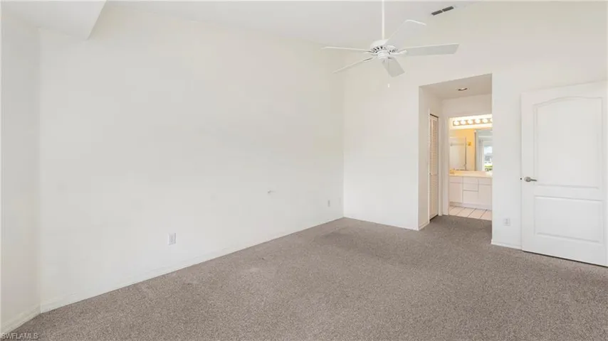 Unfurnished bedroom featuring carpet flooring, lofted ceiling, a ceiling fan, and ensuite bathroom
