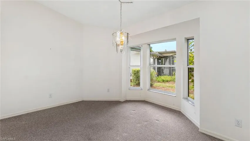 Empty room with carpet flooring and suspended lighting