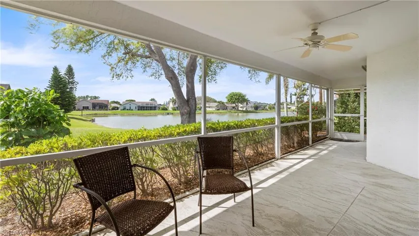 Unfurnished sunroom with a residential view, ceiling fan, and a water view