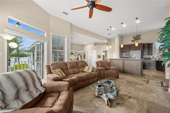 Living room with a ceiling fan, stone tile floors, and recessed lighting