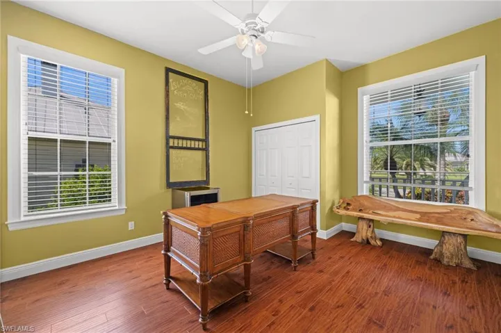 Office area with dark wood-type flooring and ceiling fan