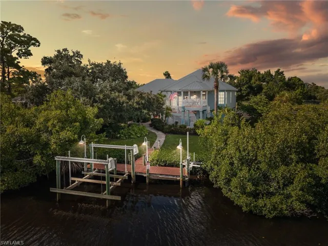 Dock area with boat lift, a water view, and a yard