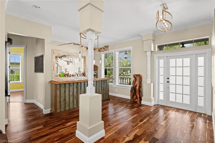Entrance foyer with crown molding, healthy amount of natural light, a chandelier, and dark wood finished floors