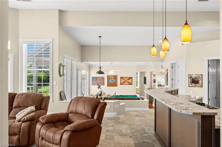Kitchen featuring hanging light fixtures, light stone counters, open floor plan, and light stone finish flooring