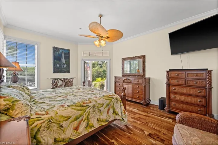 Bedroom featuring ornamental molding, access to outside, wood finished floors, and a ceiling fan