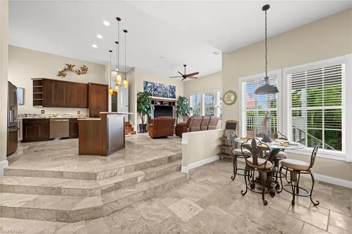 Dining room with ceiling fan, stone tile flooring, and recessed lighting