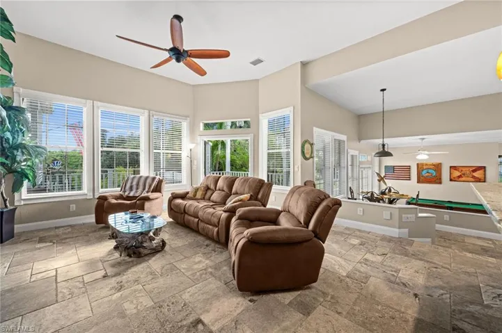 Living room featuring a ceiling fan, billiards table, and stone tile floors