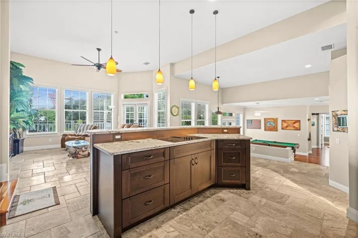Kitchen featuring ceiling fan, hanging light fixtures, dark brown cabinets, and healthy amount of natural light