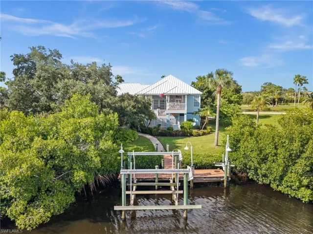 Dock with a yard, a water view, boat lift, and a balcony