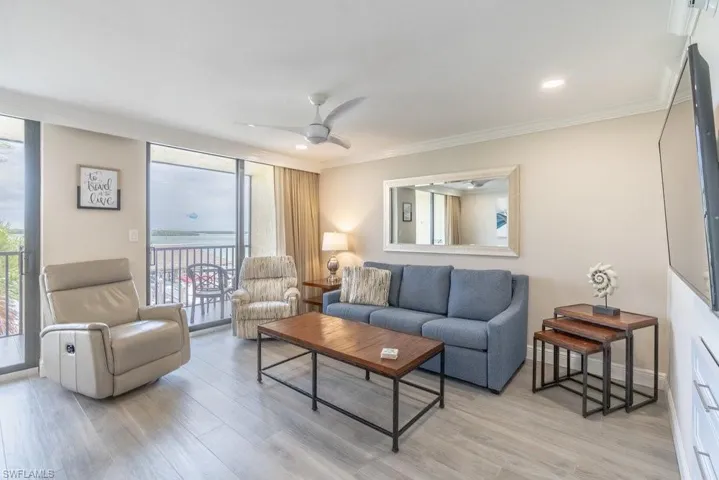 Living area with healthy amount of natural light, light wood finished floors, crown molding, and ceiling fan