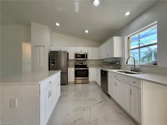 Contemporary kitchen featuring white cabinetry, light-toned countertops, and stainless steel appliances