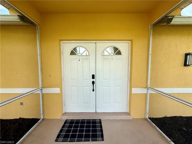 Dual panel entry doors featuring arched transom windows and stucco exterior finish