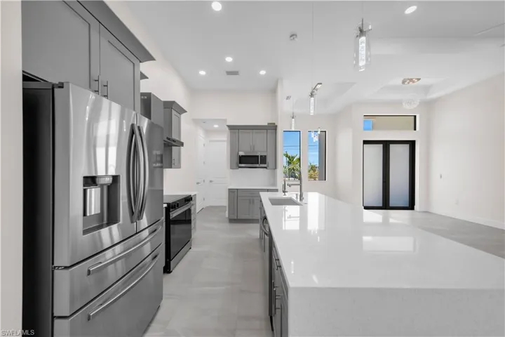 Kitchen with a sink, stainless steel appliances, recessed lighting, a large island with sink, and gray cabinetry