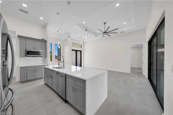 Kitchen featuring gray cabinets, visible vents, a sink, a raised ceiling, and stainless steel appliances