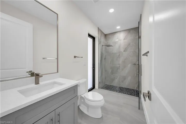 Full bathroom featuring toilet, recessed lighting, a marble finish shower, and vanity