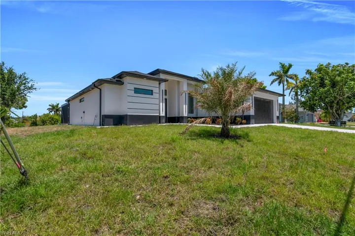 View of front of home featuring a garage, stucco siding, driveway, and a front yard