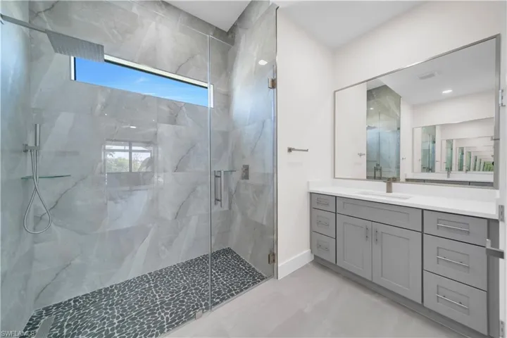 Full bathroom with a marble finish shower, a healthy amount of sunlight, marble finish floor, and vanity