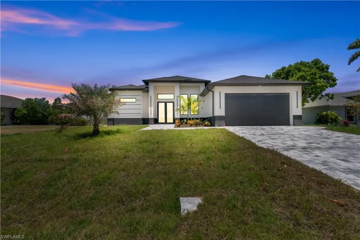 Prairie-style home with a front lawn, decorative driveway, stucco siding, french doors, and an attached garage