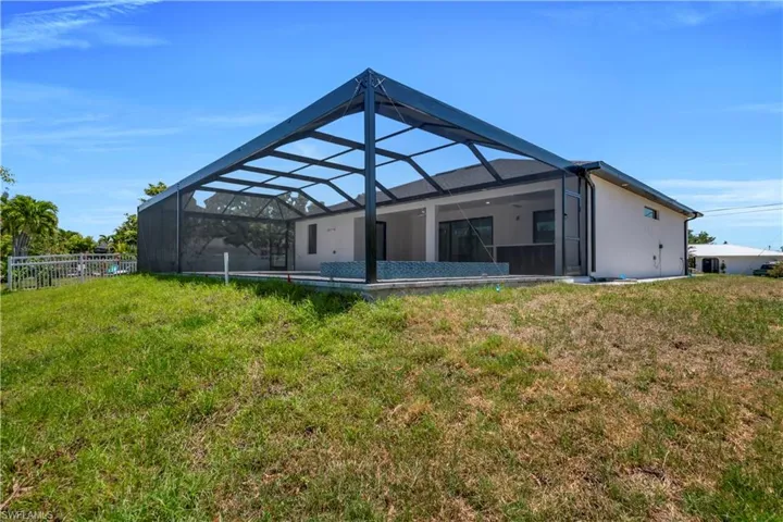 Rear view of property with a yard, fence, and glass enclosure