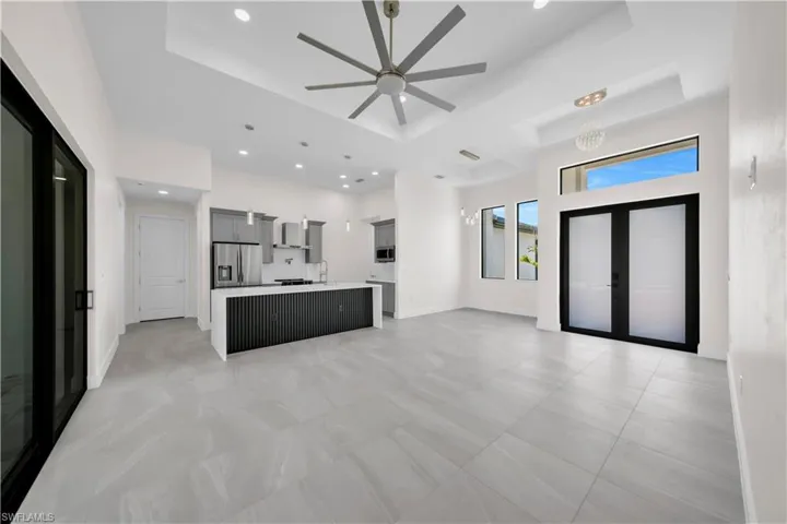 Unfurnished living room featuring a raised ceiling, french doors, a ceiling fan, baseboards, and recessed lighting