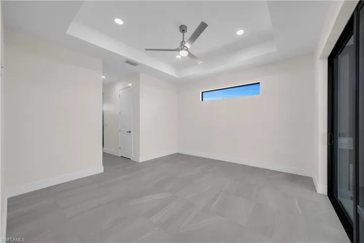 Unfurnished room featuring baseboards, ceiling fan, a tray ceiling, and visible vents