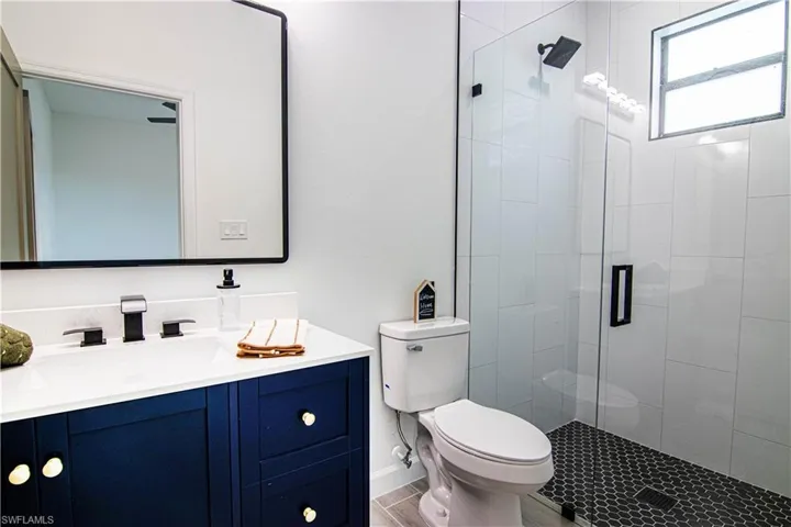 Bathroom featuring hardwood / wood-style flooring, vanity, toilet, and a shower with shower door