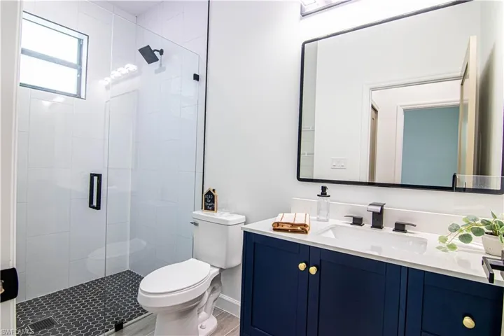 Bathroom featuring vanity, hardwood / wood-style flooring, toilet, and a shower with door