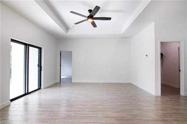 Unfurnished room featuring ceiling fan, light hardwood / wood-style floors, and a raised ceiling