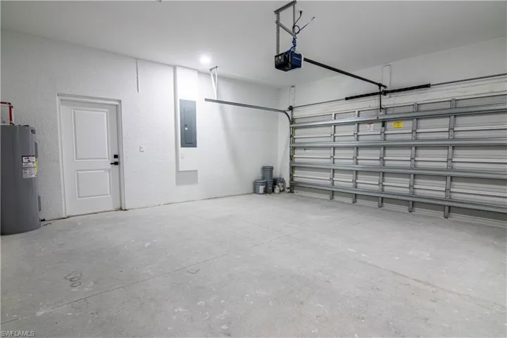 Garage featuring electric panel, water heater, and a garage door opener