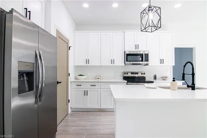Kitchen featuring appliances with stainless steel finishes, white cabinetry, pendant lighting, and sink