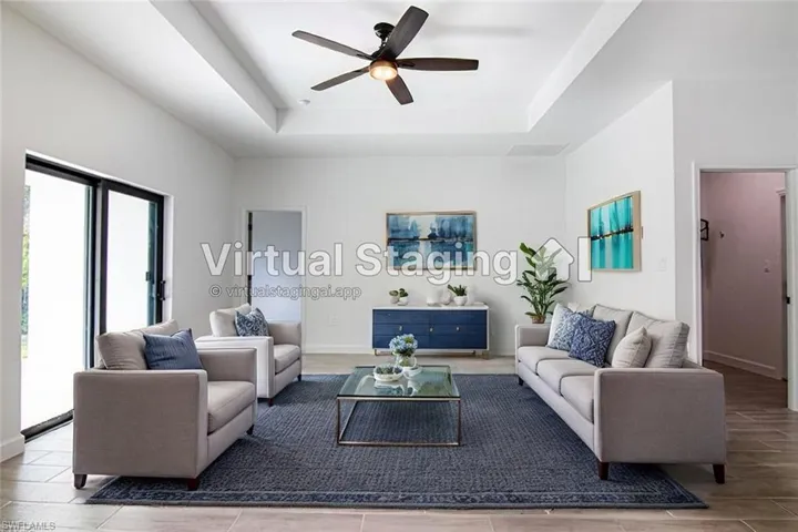 Living room featuring a tray ceiling, ceiling fan, and light hardwood / wood-style floors